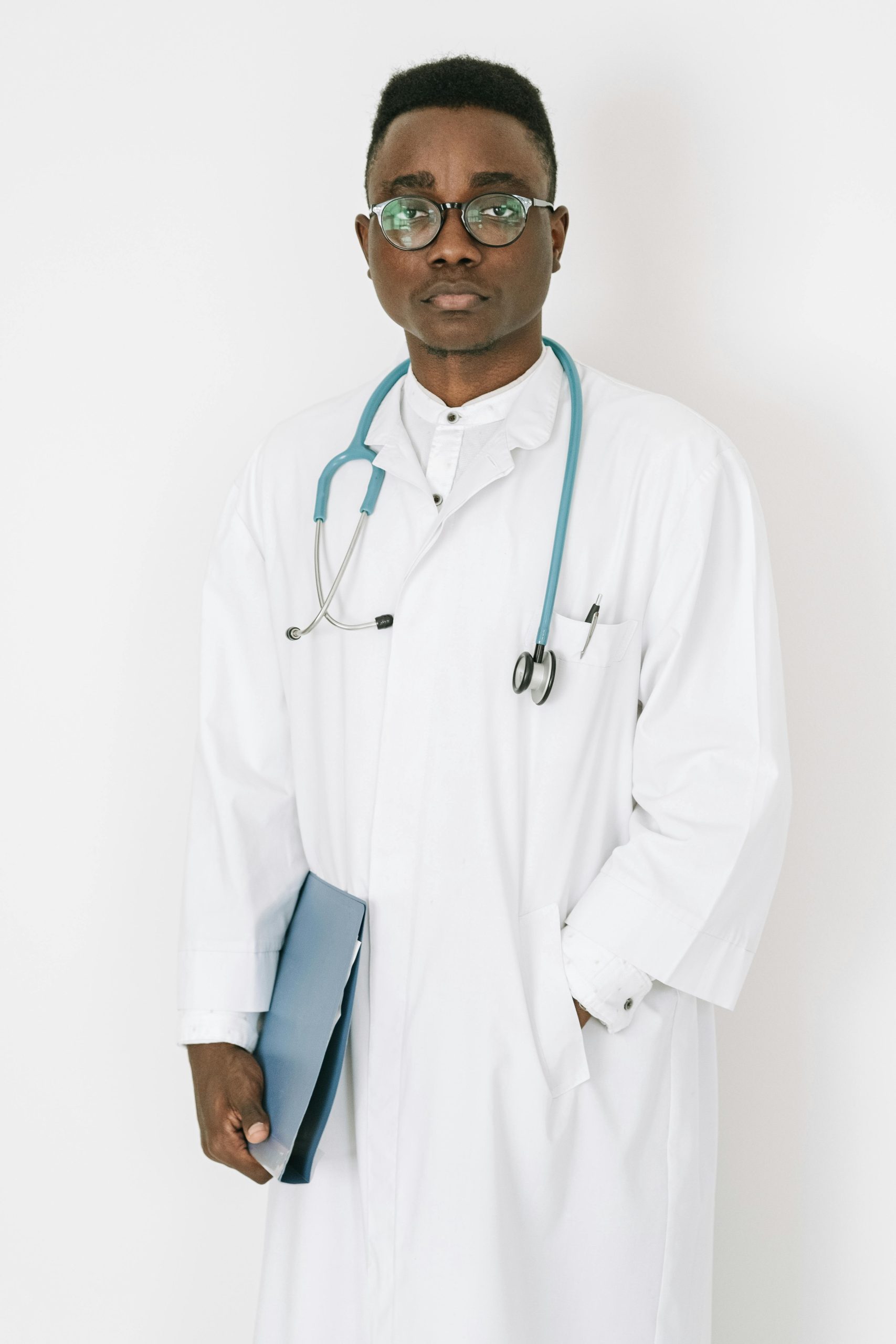 Confident doctor with stethoscope and clipboard standing against white background.